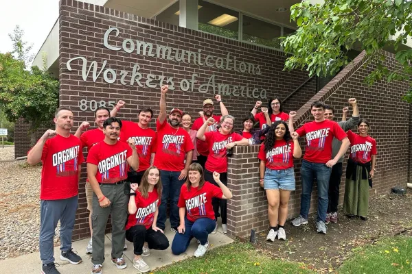 A group of union members wearing a red shirts put their fists in the air