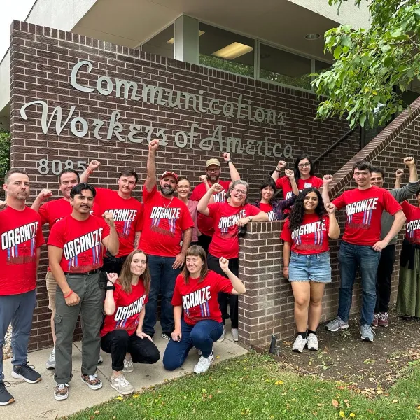 A group of union members wearing red shirts put their fists in the air